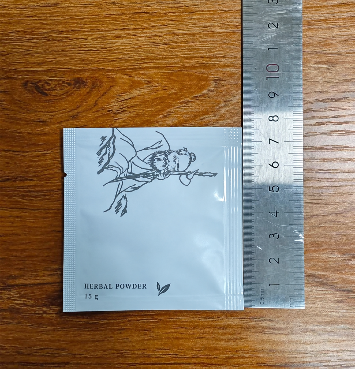 木质台面上草本粉小袋的热封边与侧面易撕口，旁边放有金属尺